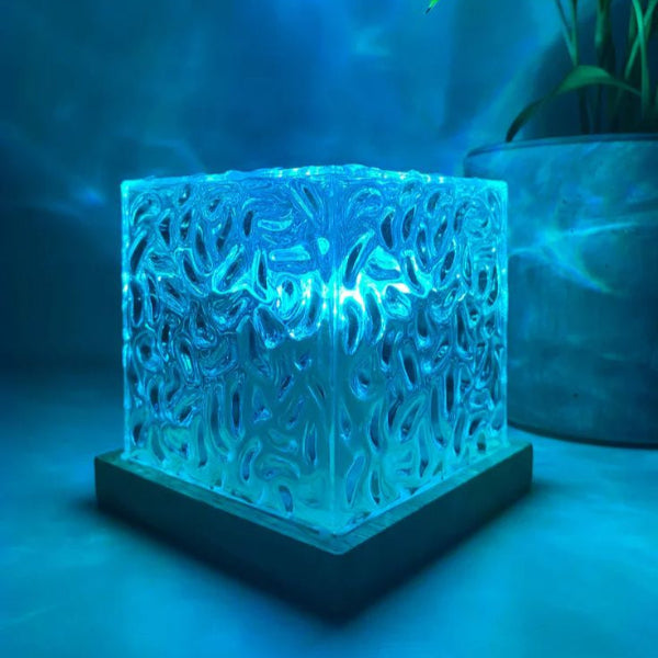 Ocean wave lamp place on a table with a plant in the background behind it